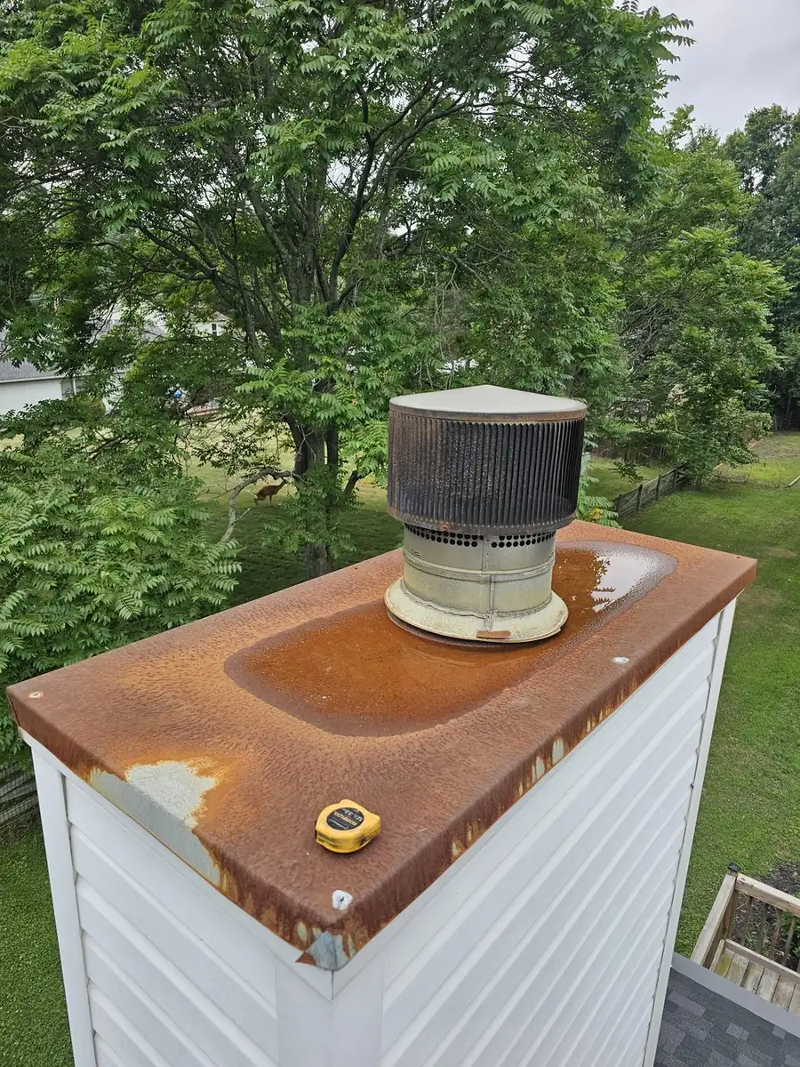 Green and Clean masonry technician working on a chimney roofline