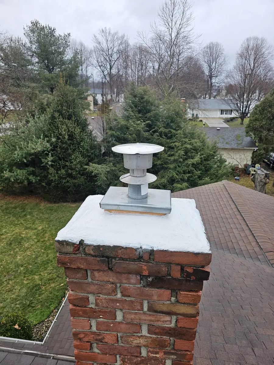 Green and Clean technician repairing a chimney chase on a Cleveland area roof