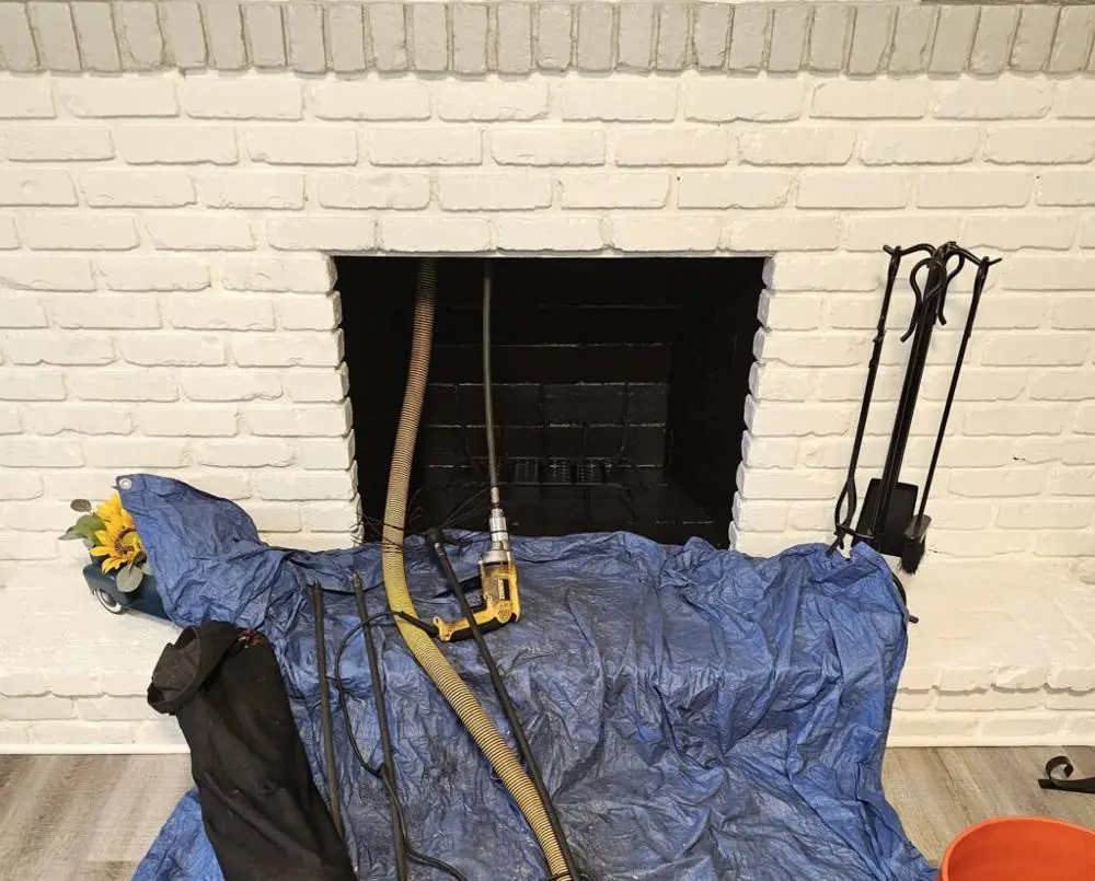 Fireplace prepared for a chimney cleaning with tarp, rods and vacuum hose