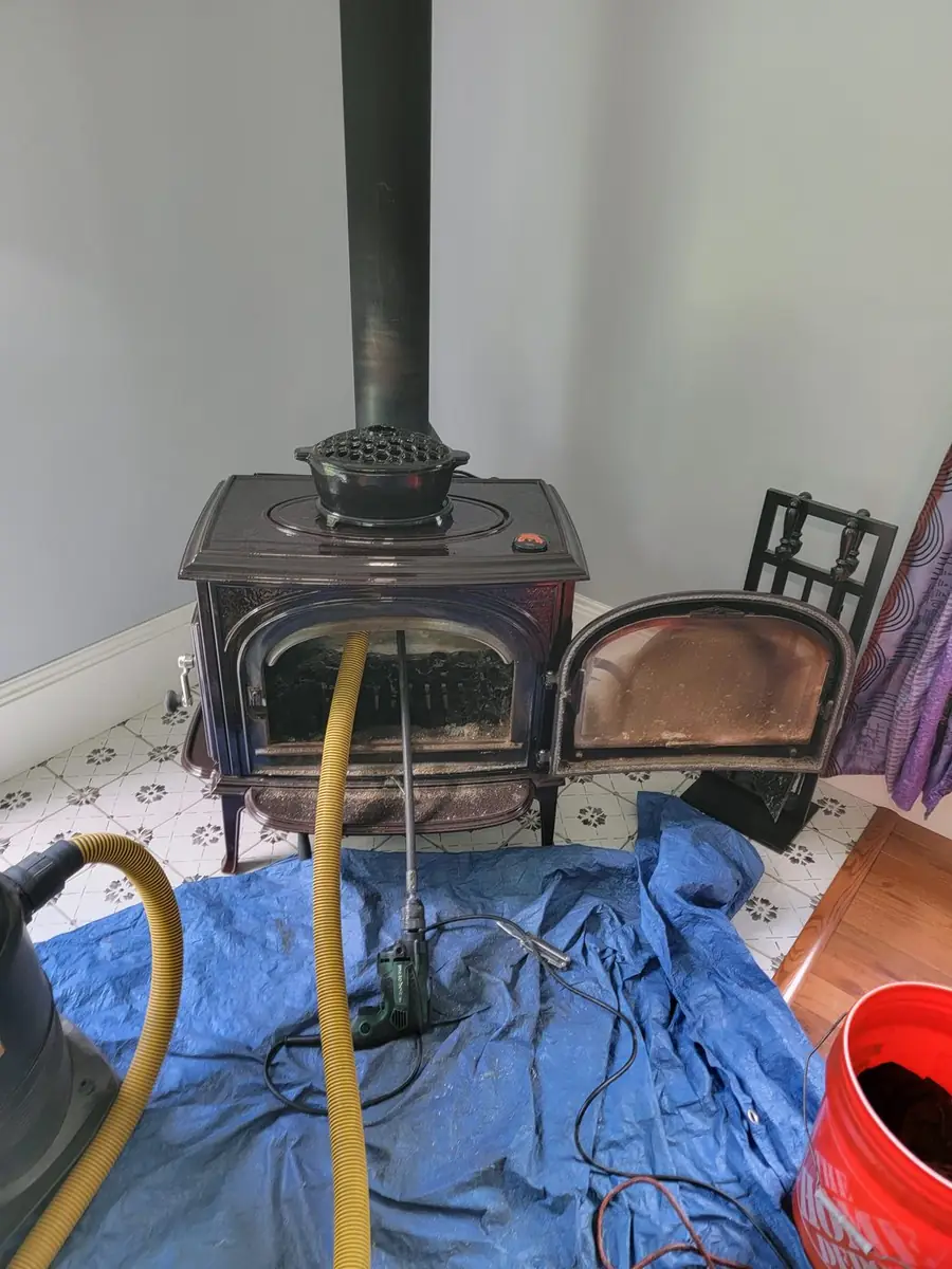 Technician with sweep gear and HEPA vacuum at a fireplace