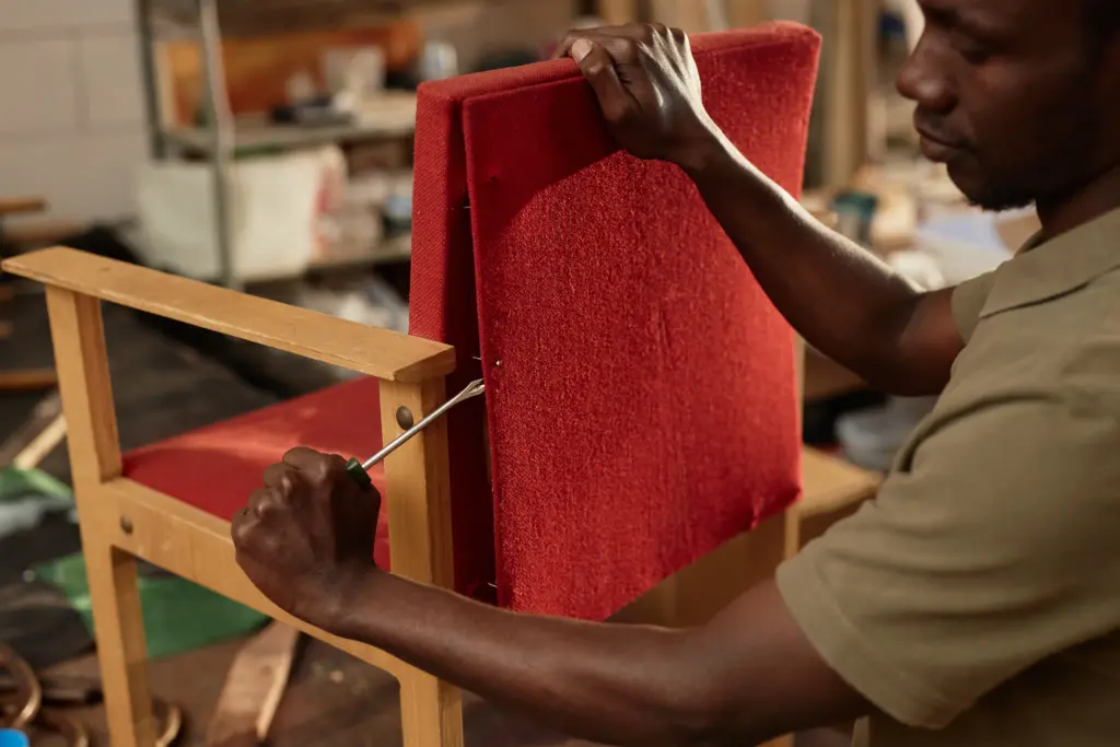 black man refurbishing armchair in carpentry works