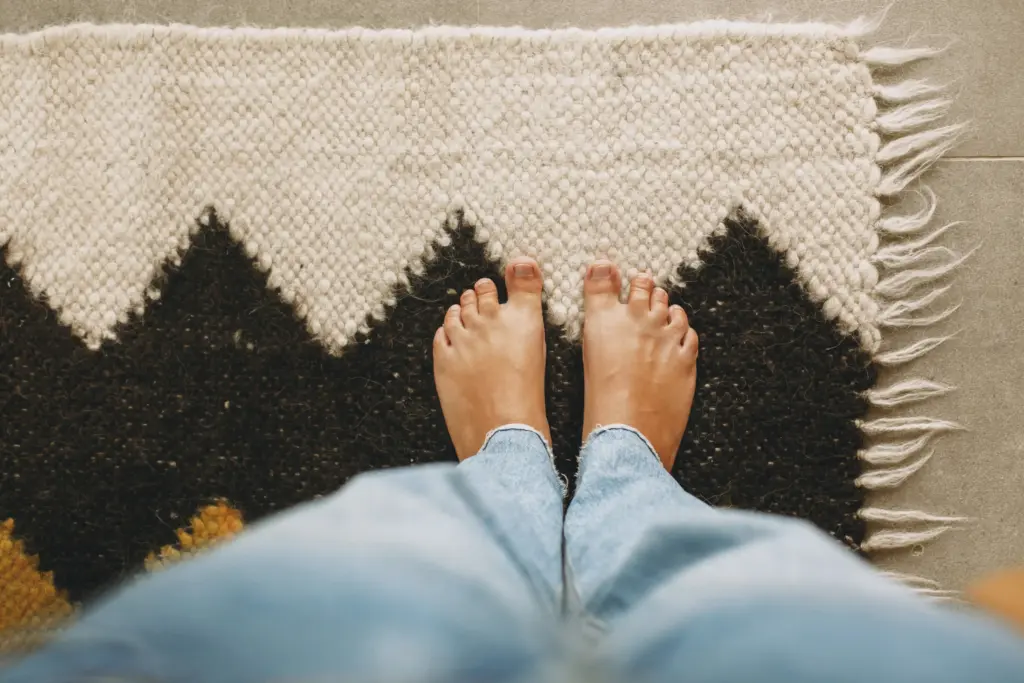 feet on cozy woolen rug on background of concrete