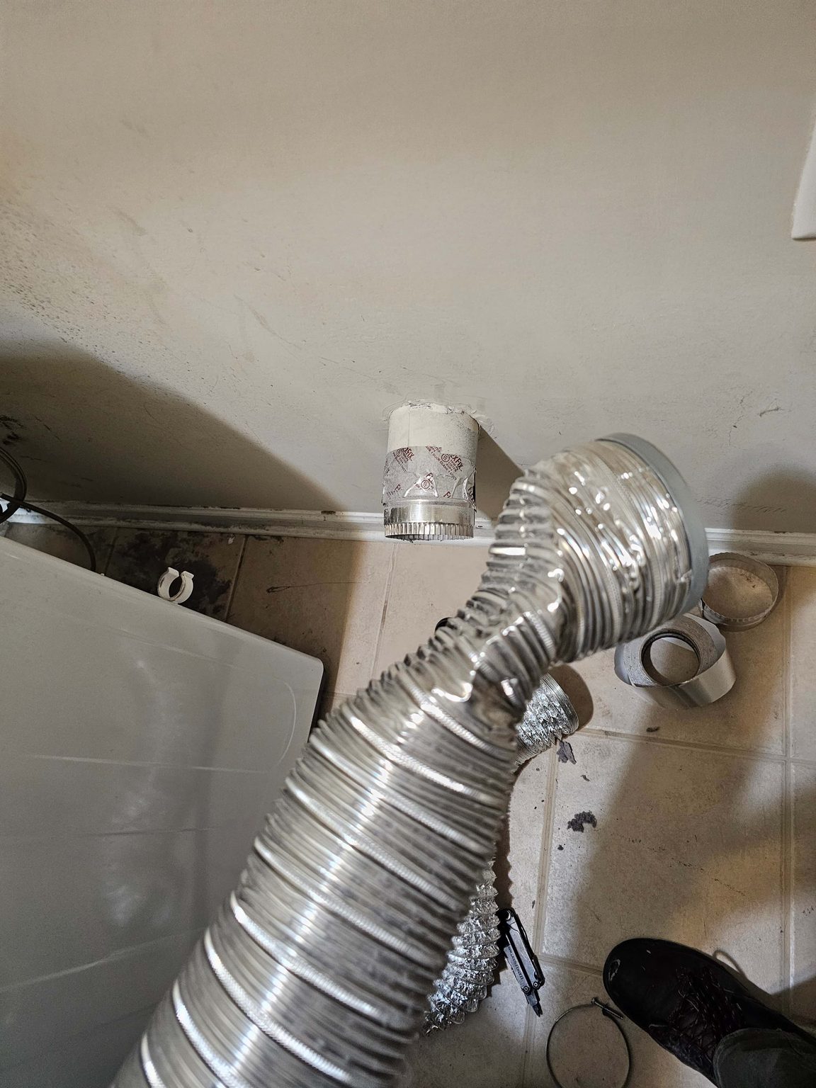 Flexible foil dryer vent duct connected to the wall exhaust behind a dryer